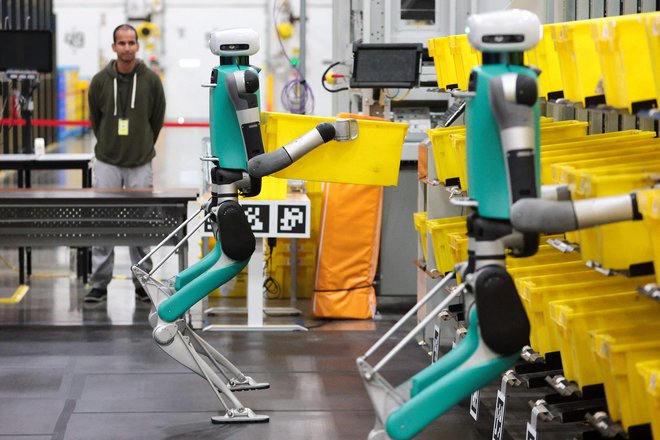 Logistična družba Amazon v svojih skladiščih testira robote, ki potiskajo vozičke. FOTO: Jason Redmond/AFP