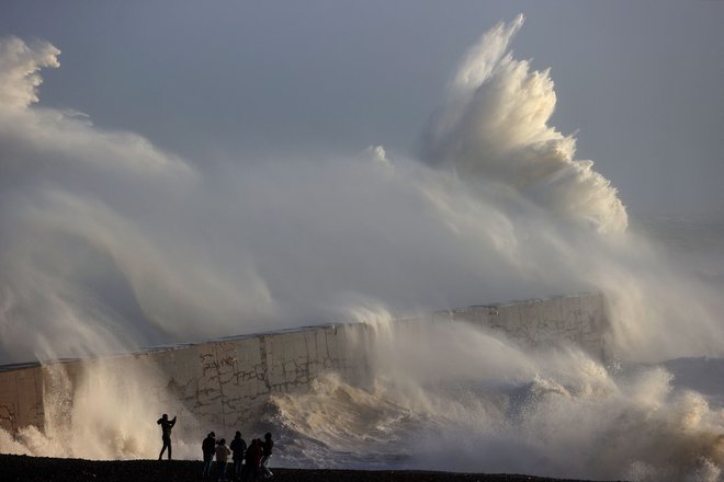 Oseba fotografira valove, ki se lomijo ob valobran v Newhavnu, saj je nevihta Henk prinesla močan veter in obilno deževje v večji del južne Anglije. Foto: Adrian Dennis/Afp