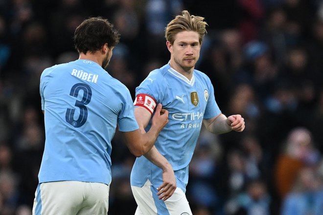 Ruben Dias in Kevin De Bruyne med izmenjavo kapetanskega traku Manchester Cityja. FOTO: Paul Ellis/AFP