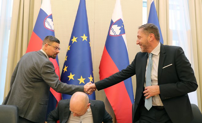 Jakob Počivavšek, vodja pogajalske skupine reprezentativnih sindikatov javnega sektorja, in finančni minister Klemen Boštjančič sta si po podpisu dogovora segla v roke. FOTO: Blaž Samec/Delo