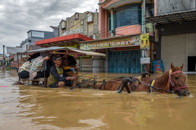 Prebivalci s konjsko vprego bežijo iz poplavljenega indonjezijskega mesta Dayeuhkolot, potem ko je reka zaradi močnega deževja prestopila meje. Foto: Timur Matahari/Afp
