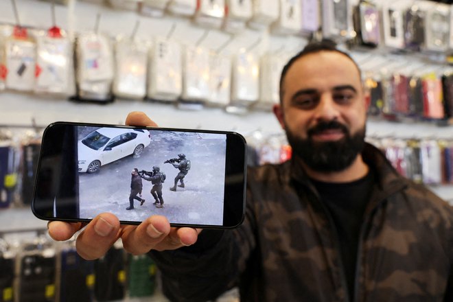 Palestinec Bahaa Abu Ras, ki so ga izraelske enote med racijo uporabile kot živi ščit, na svojem mobilnem telefonu prikazuje videoposnetek incidenta v Duri pri Hebronu na Zahodnem bregu, ki ga je zasedel Izrael. Foto; Mussa Issa Qawasma/Reuters