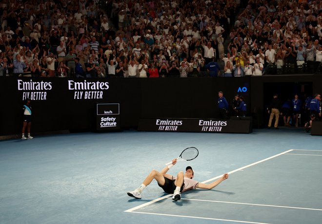 Jannik Sinner se je zgrudil na tla po imenitni zmagi. FOTO: Eloisa Lopez/Reuters