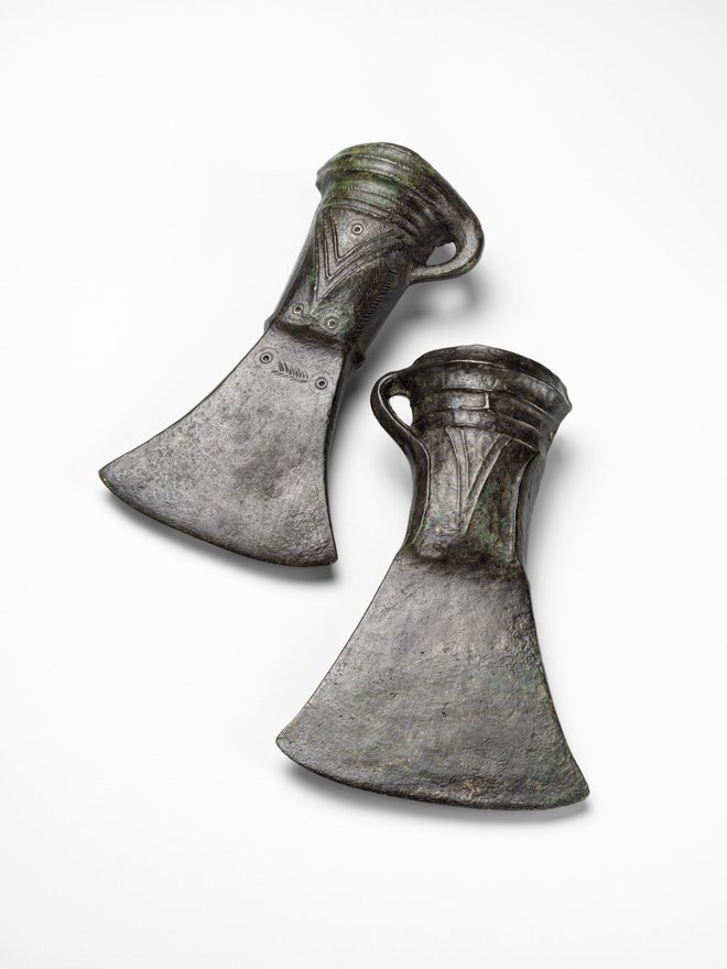 V pozni bronasti dobi so se v srednjo Evropo z vzhoda razširile bronaste tulaste sekire. Pri teh sekirah je bilo nasadišče vdeto v cevast tul in dodatno pričvrščeno z jermenjem, privezanim na stransko ušesce. Sekiri iz Ljubljanice pri Bevkah iz 11.–10. stoletja pr. n. št. sta v času kulture žarnih grobišč mlajši različici tulastih sekir, bogato okrašeni z ulitim rebrastim in vtolčenim okrasom. FOTO: Tomaž Lauko ©Narodni muzej Slovenije
