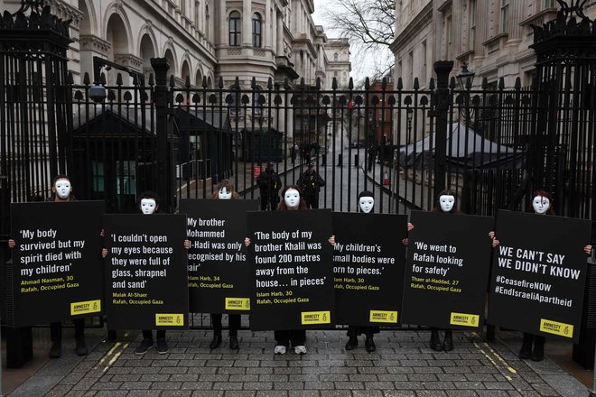 Aktivisti organizacije Amnesty International med tiho vigilijo pred vrati Downing Steet v središču Londona. Pozivajo vlado Združenega kraljestva, naj uporabi vsa razpoložljiva sredstva in pritisne na izraelske oblasti, da prekličejo odločitev o napadu na Rafo. Ministrstvo za zdravje v Gazi, je sporočilo, da je bilo na tem ozemlju ubitih najmanj 28 576 ljudi. Vojno je sprožil Hamasov napad na Izrael 7. oktobra, v katerem je umrlo približno 1.160 ljudi. Od 250 talcev, ki jih je Hamas zajel med napadom 7. oktobra, naj bi jih bilo v Gazi še vedno približno 130. Izrael pravi, da jih je 29 domnevno mrtvih. Foto: Daniel Leal/Afp