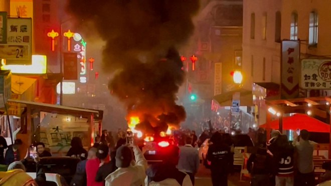 Waymov robotski taksi v ognju sredi San Francisca, potem ko so ga neznani storilci razbili in vanj metali rakete. FOTO: Michael Vandi/Reuters