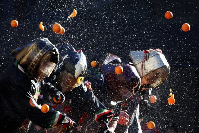 Navdušenci sodelujejo v boju s pomarančami med vsakoletno karnevalsko bitko v Ivrei v Italiji. Foto: Guglielmo Mangiapane/Reuters