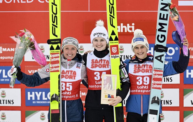 Zmagovalki Niki Križnar (na sredini) sta družbo na odru za najboljše smučarske skakalke v Lahtiju delali Avstrijki Jacqueline Seifriedsberger (levo) in Eva Pinkelnig (desno). FOTO: Vesa Moilanen/AFP