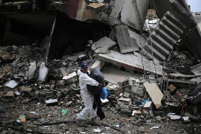 Palestinec med ruševinami uničenih stavb nosi svoje uborno imetje. FOTO: AFP