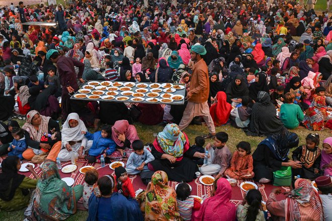 Prostovoljci delijo brezplačno hrano, medtem ko se muslimanski verniki zbirajo, da bi prekinili post med islamskim svetim mesecem ramadan v Lahoreju. Foto: Arif Ali/Afp