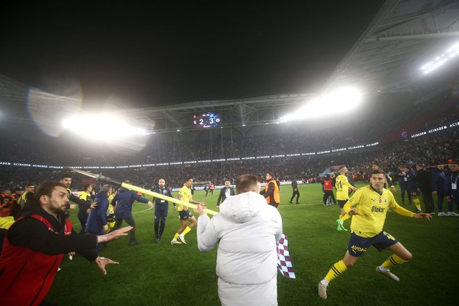 Po zadnjem sodnikovem žvižgu se je igrišče spremenilo v ring, nogometaše Fenerbahčeja so napadli navijači Trabzonsporja.  FOTO: Handout/AFP