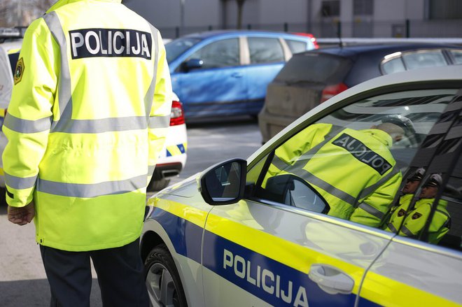 Policist pri službenem vozilu. Fotografija je simbolična. FOTO: Leon Vidic/Delo