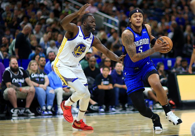 Paolo Banchero (z žogo) in Draymond Green med tekmo Orlanda in Golden Stata. FOTO: Mike Ehrmann/AFP