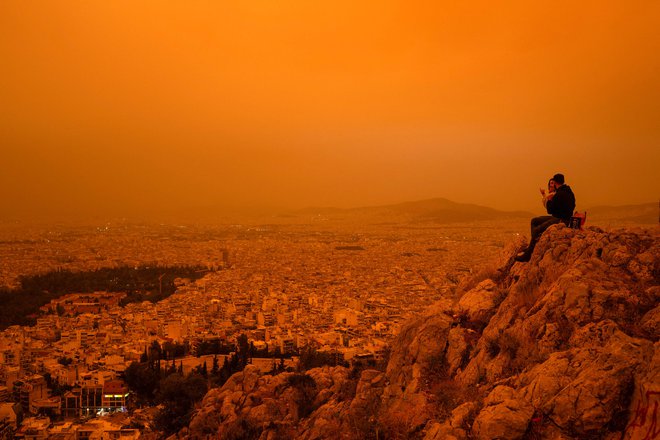 Nad Atene se je spustila dramatična oranžna meglica, ko je veter nad južno Grčijo prinesel tone puščavskega prahu iz afriške Sahare. Po besedah strokovnjakov je to eden najhujših tovrstnih izrednih vremenskih dogodkov, ki so od leta 2018 prizadeli Grčijo. Iz Sahare se na leto dvigne od 60 do 200 milijonov ton puščavskega prahu, večina se hitro spusti na zemljo, majhni delci pa prepotujejo velike razdalje. Foto: Angelos Tzortzinis/Afp