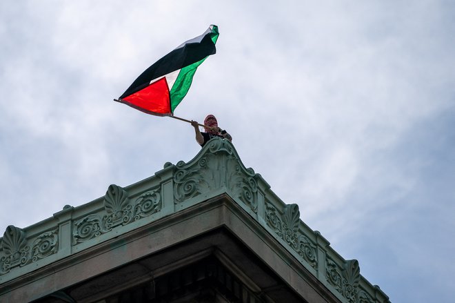 Protestnik s palestinsko zastavo na strahi objekta v okviru newyorške univerze Columbia. FOTO: David Dee Delgado/Reuters