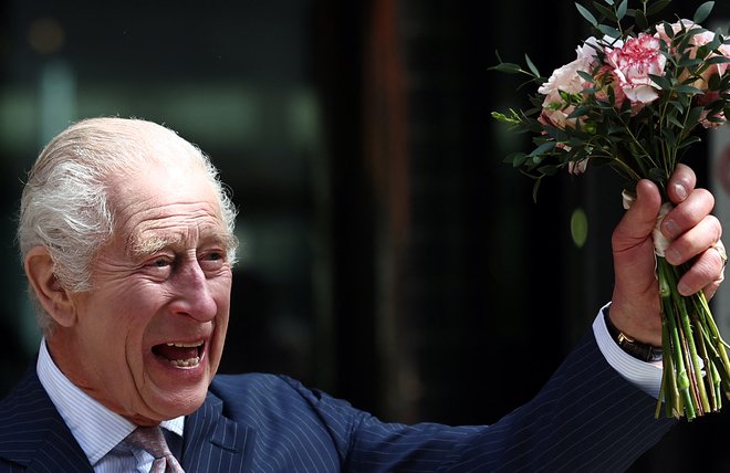 Kralj Karel III., ki so ga okronali pred natanko letom dni, se še vedno zdravi za rakom. Tako je pomahal s cvetjem oboževalcem pred centrom za zdravljenje raka Macmillan v Londonu, ki ga je po daljši odsotnosti iz javnosti izbral za svoj prvi obisk. FOTO: Henry Nicholls/AFP