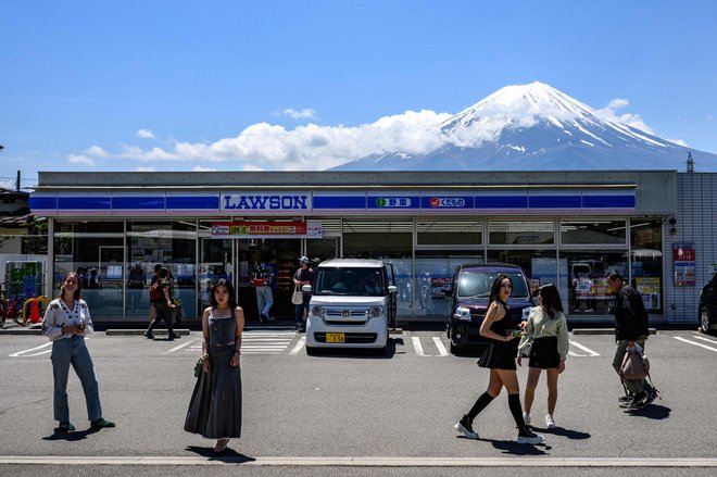 Turisti v mestu Fujikawaguchiko še zadnjič slikajo sveto jaoponsko goro. Kmalu  jo bodo zakrili. Zaradi turistov, seveda. Foto Philip Fong Afp
