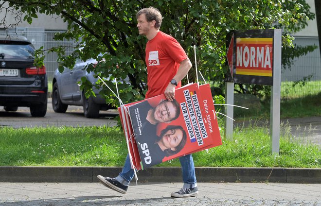 Prostovoljec s plakatom Matthiasa Eckeja FOTO: Matthias Rietschel/Reuters