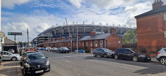 Tipične skromne opečnate hišice v dublinskem delavskem predmestju Ballybough, v irščini poimenovanem An Baile Bocht oziroma »revno mesto«. V ozadju je eden največjih stadionov v Evropi, The Croker, ki sprejme kar 82.300 gledalcev. Namenjen je predvsem hurlingu in drugim irskim športom, na njem pa redno koncertirajo tudi U2, Rolling Stones in druge rock skupine. FOTO: Miha Jenko/Delo