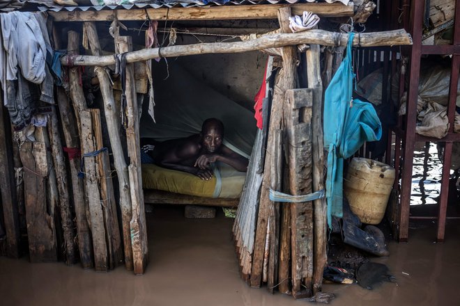 Moški ocenjuje višino vode iz svoje postelje na poplavljenem območju v Garissi. Kenija se spopada z eno najhujših poplav v novejši zgodovini, ki je zadnja v vrsti vremenskih katastrof po tednih ekstremnih padavin, ki jih znanstveniki povezujejo s spreminjajočim se podnebjem. Vsaj 257 ljudi je umrlo, več kot 55.000 gospodinjstev pa je bilo razseljenih, saj so kalne vode zalile cele vasi, uničile ceste in poplavile jezove. Foto: Luis Tato/Afp