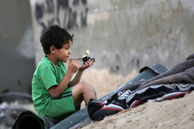 Palestinski deček med igro v oblegani Gazi FOTO: AFP