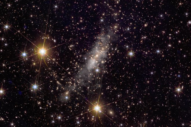 Na posnetku jate galaskij Abell 2390 je več kot 50.000 galaksij. Vidno je, kako deluje gravitacijsko lečenje, ko masivni objekti ukrivijo svetlobo in razkrivajo, kaj se skriva neposredno za njimi. To je ključna tehnika za raziskovanje oddaljenega vesolja, s tem se lahko tudi posredno merit količino in razporeditev temne snovi v sami jati galaksij in tudi drugod. FOTO: Esa/Euclid/Nasa 

 