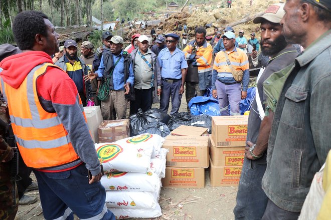 Humanitarni delavci so se zbrali okrog paketov pomoči, ki so jih nato razdelili. FOTO: New Porgera Limited via Reuters