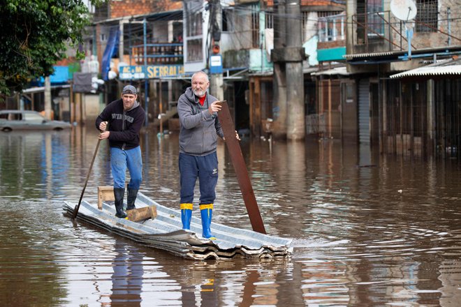 Moška veslata po poplavljeni ulici v soseski Vila Farrapos v brazilskem mestu Porto Alegre. Brazilske oblasti so včeraj poročale o povečanem številu primerov leptospiroze, bakterijske bolezni, ki jo prenašajo podgane, na poplavljenem jugu države, katere deli so pod vodo že mesec dni. Po najnovejših podatkih zdravstvenega sekretariata zvezne države Rio Grande do Sul je potrjeno, da je za to boleznijo umrlo pet ljudi, še devet smrtnih primerov pa preiskujejo. Foto: Silvio Avila/Afp