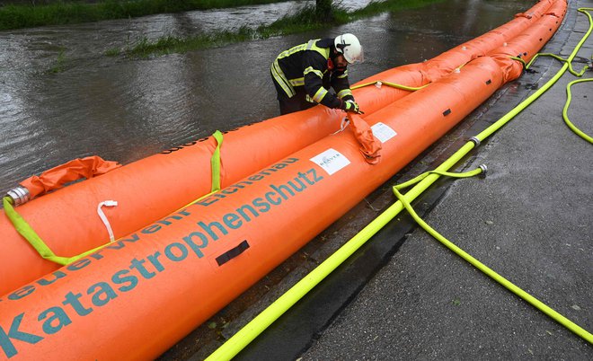 Gasilci skušajo vodo preusmeriti z zasilnimi zajezitvami. FOTO: Michaela Stache/AFP