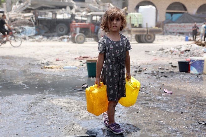 Palestinsko dekle nosi posode z vodo v begunskem taborišču Jabalia na severu Gaze. ZDA so pozvale Varnostni svet Združenih narodov, naj sprejme najnovejši predlog o premirju v Gazi, ki ga je predstavil ameriški predsednik Joe Biden. Izraelska vojska je medtem potrdila smrti štirih izraelskih talcev v ujetništvu. Foto: Omar Al Qatta/Afp