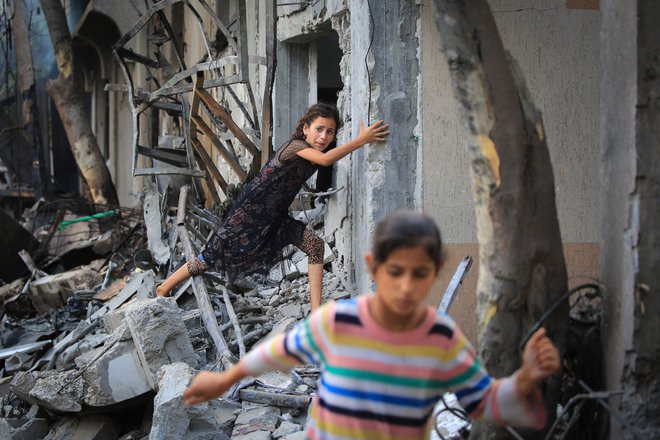 Palestinska deklica na kupu ruševin. FOTO: Eyad Baba/Afp