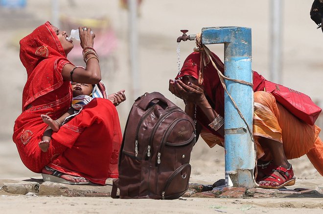 V vročem poletnem dnevu v Prayagraju ženske gasijo žejo z vodo iz pipe. Vročinski val v Indiji je najdaljši, kar jih je kdajkoli prizadelo to državo, je včeraj povedal glavni vladni strokovnjak za vreme in opozoril, da se bodo ljudje soočali z vse višjimi temperaturami. Del severne Indije je od sredine maja zajel vročinski val, saj so se temperature povzpele nad 45 stopinj Celzija. Foto: Anil Shakya/Afp