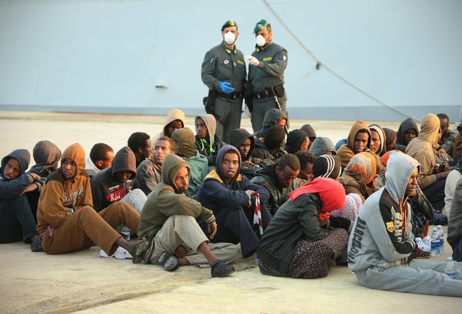 Begunci in policista v pristanišču Augusta na Siciliji. Italija, 25. aprila 2015. FOTO: Jure Eržen/Delo