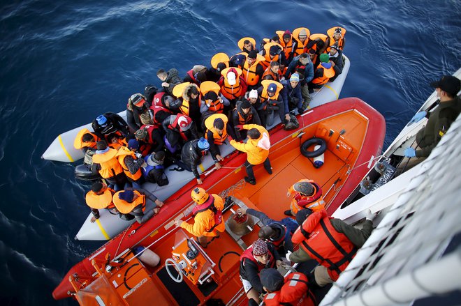 Begunci in migranti se vkrcajo na ladjo turške obalne straže, 2015. FOTO: Reuters