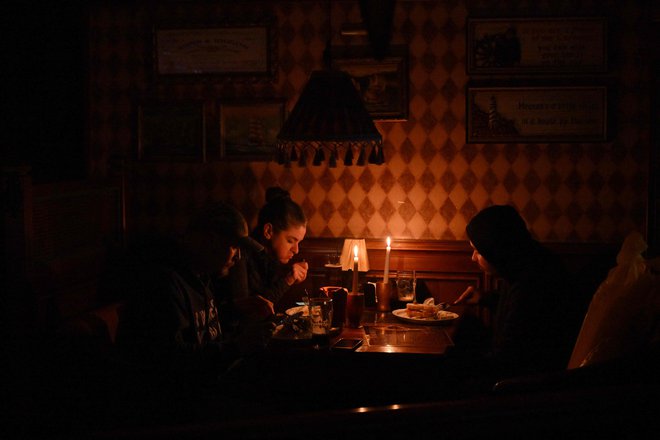 Večerja ob svečah, ko zmanjka elektrike. FOTO: Sergei Supinsky/AFP