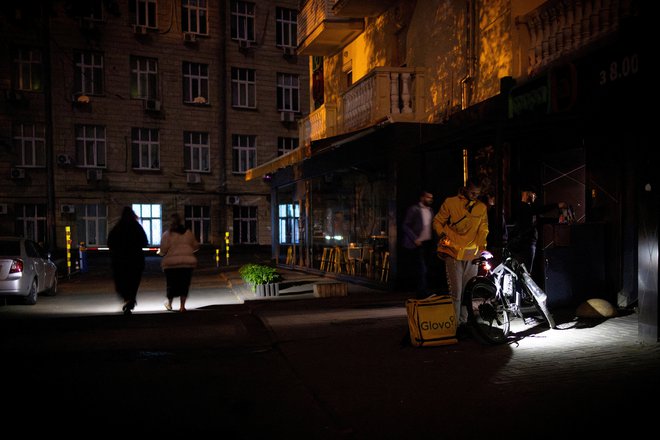 Ljudje si z baklami osvetljujejo pot do trgovine in iz nje. FOTO: Thomas Peter/Reuters