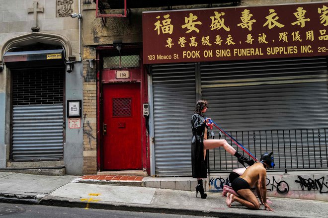 V kitajski četrti na Manhattenu ženska, oblečena kot domina, pozira fotografu z moškima, ki igrata njenega sužnja z živalsko masko. Foto: Charly Triballeau/Afp