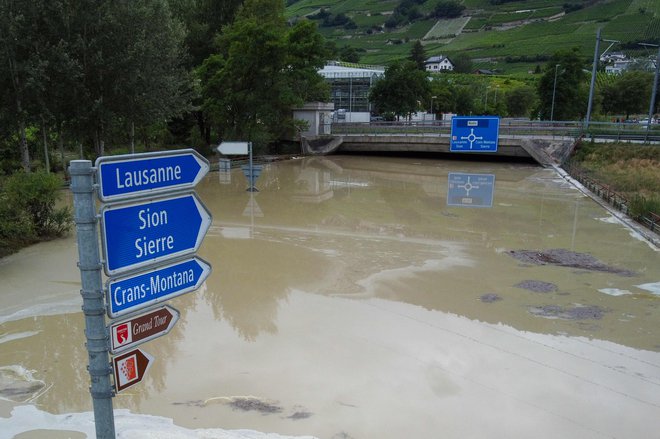 Poplavljena cesta v Švici, kjer je v neurju ta konec tedna življenje izgubilo pet ljudi.  FOTO: Boris Herger/Afp