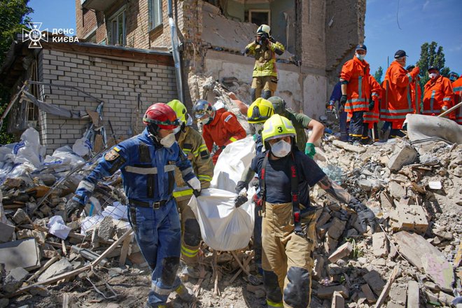 Danes so izpod ruševin v stanovanjske zgradbe v ukrajinski prestolnici potegnili truplo 21. žrtve včerajšnjih ruskih obstreljevanj z raketami dolgega dosega. FOTO: Reuters