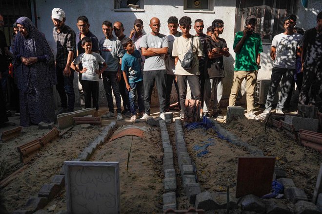 Žalujoči pred grobovi družinskih članov, trupla katerih so jim bila predana za pokop iz začasnih grobov v bolnišnici Al Amal v Han Junisu na jugu Gaze. FOTO: Bashar Taleb/AFP