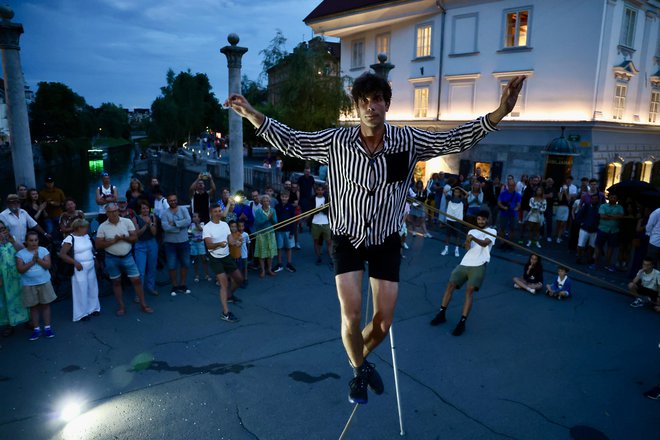 Andrej Tomše je edini ulični gledališčnik in cirkusant, ki ga lahko vidimo na ljubljanskih ulicah. Takole je sinoči zabaval občinstvo na Šuštarskem mostu. FOTO: Voranc Vogel