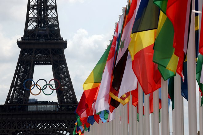 Pod Eifflovim stolpom vihrajo zastave udeleženk olimpijskih iger. Foto Yves Herman/Reuters