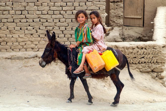 Afganistanski deklci jezdita osla po ulici v okrožju Argo v provinci Badakšan. Foto: Omer Abrar/Afp