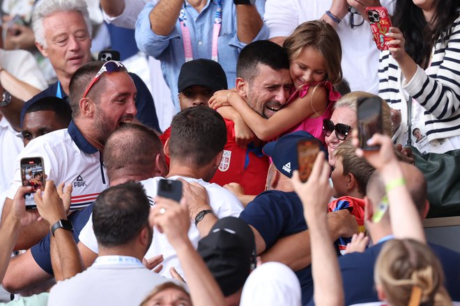 Po olimpijskem zmagoslavju je Novak Đoković vzel v naročje hčerkico Taro. FOTO: Claudia Greco/Reuters