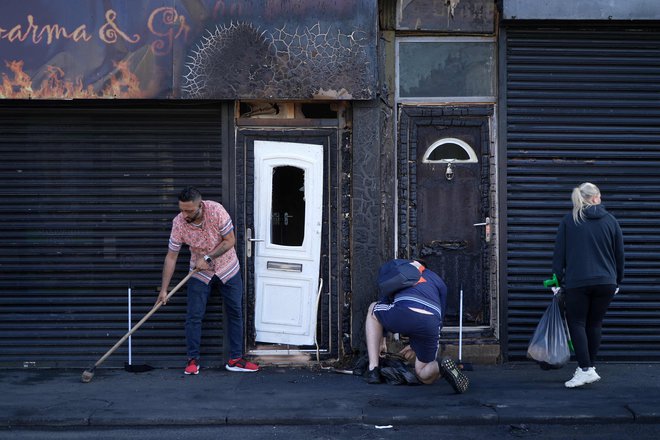 Lastniki lokalov med odstranjevanjem posledic izgredov v Middlesbroughu FOTO: Yelim Lee/Afp