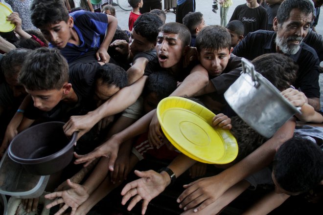 Sestradani Palestinci čakajo v vrsti za hrano. FOTO: Mahmoud Issa/Reuters