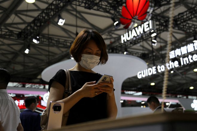 FILE PHOTO: A visitor checks a mobile phone near the Huawei logo during the Mobile World Congress in Shanghai, China June 28, 2023. REUTERS/Nicoco Chan/File Photo