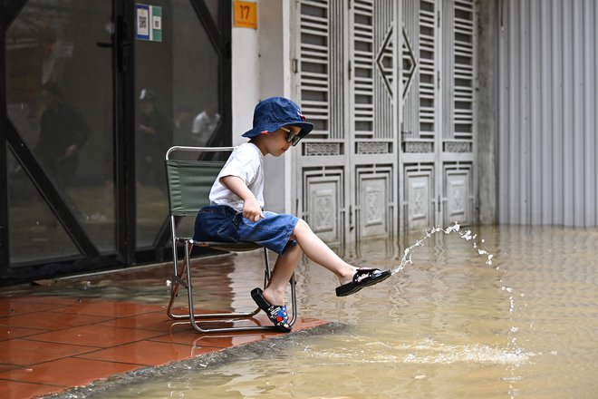 TOPSHOT - A children plays with flood waters on a street in Hanoi on September 12, 2024, as heavy rains in the aftermath of Typhoon Yagi brought flooding to northern Vietnam. (Photo by NHAC NGUYEN/AFP) Foto Nhac Nguyen Afp