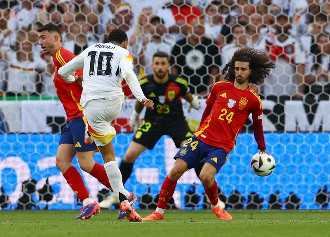 Španski branilec Marc Cucurella je takole v kazenskem prostoru z roko zaustavil strel Nemca Jamala Musiale. FOTO: Lee Smith/Reuters