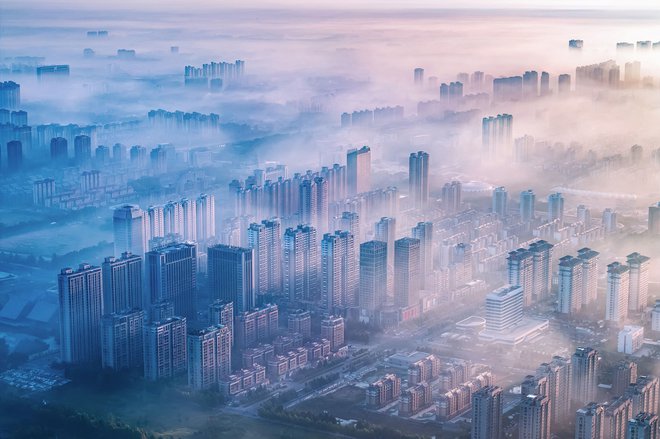 Pogled na sončno svetlobo, ki zjutraj kuka skozi meglo nad stanovanjskimi stavbami v Lianyungangu v provinci Jiangsu na vzhodu Kitajske. Foto: Stringer/Afp